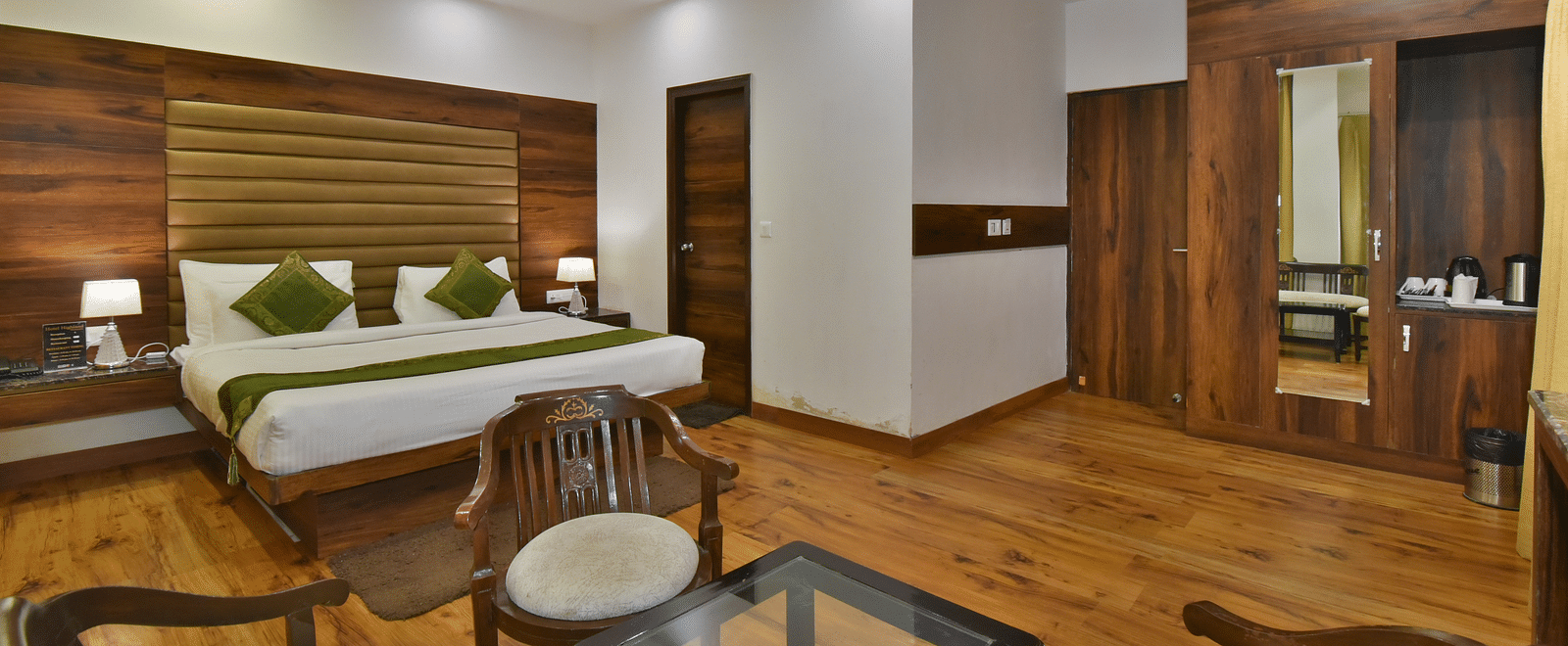 A large bed placed in front of two sofas at the Luxury Room Without Balcony at DLS Highland Resort and Spa, Mussoorie.